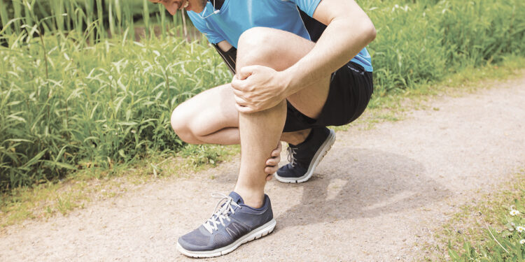 Personne tenant sa jambe pour soulager une crampe musculaire