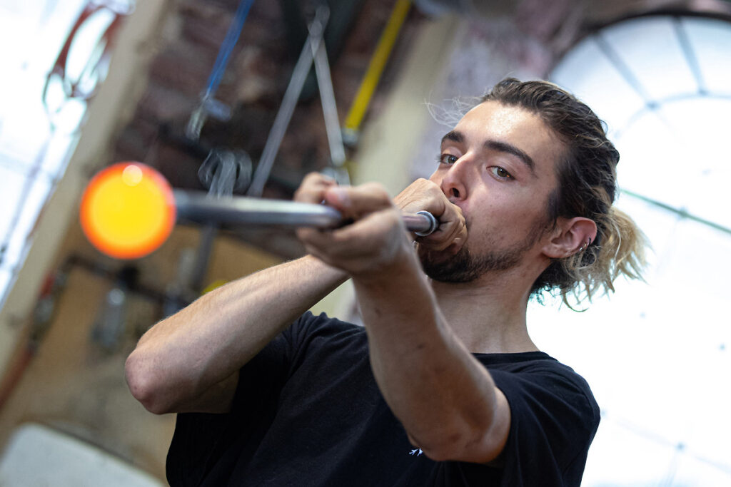Verrier en train de souffler une boule de verre en fusion dans un atelier du CIAV de Meisenthal.