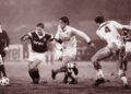 Sylvain Kastendeuch face à Bernard Lacombe lors d’un match des années 1980, sous la pluie, dans un duel serré au milieu du terrain.