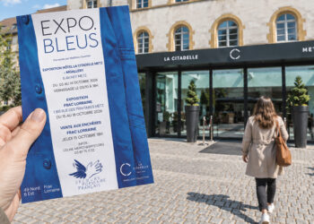 Une femme tenant le flyer Expo Bleus devant La Citadelle à Metz