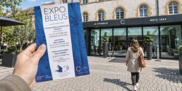 Une femme tenant le flyer Expo Bleus devant La Citadelle à Metz